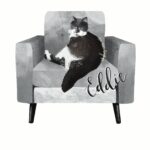 A digitally drawn grey and white cat, with his name, "Eddie" in digitally calligraphy. - Eddie is lounging on a modern, grey leather armchair.