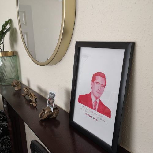 A white background print with Michael Scott looking directly at the viewer whilst wearing a pinstripe suit and tie. The quote reads "I'm not superstitious but I am a little stitious", and is in a typewriter style font. The portrait is pink and red. Available in A5, A4 or A3 - pictured is the A4 size. The print is printed onto 230gsm Matte Photo Paper, with Recycled Cardboard + Compostable See-through bags to keep them safe.